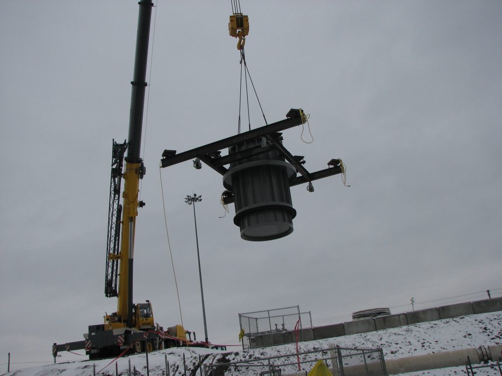 a crane suspending a piece of equipment at a nuclear tank site
