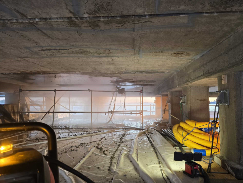Wider view of the bridge deck underside and exposed rebar,