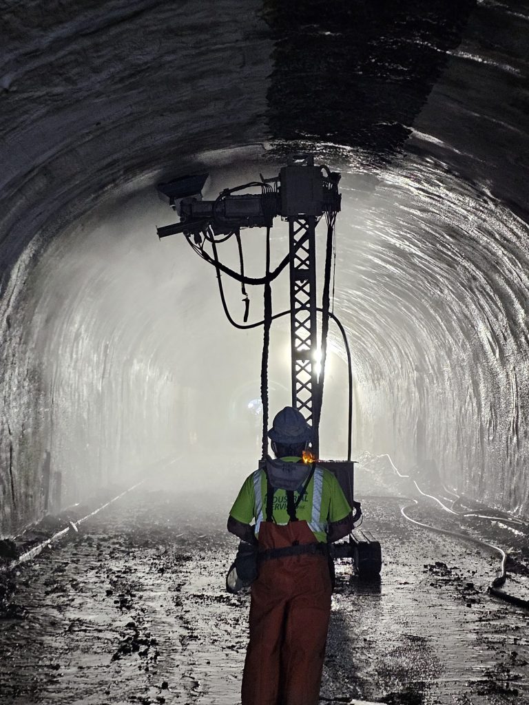 An operator controlling the robot as it performs hydrodemolition on the tunnel arch.