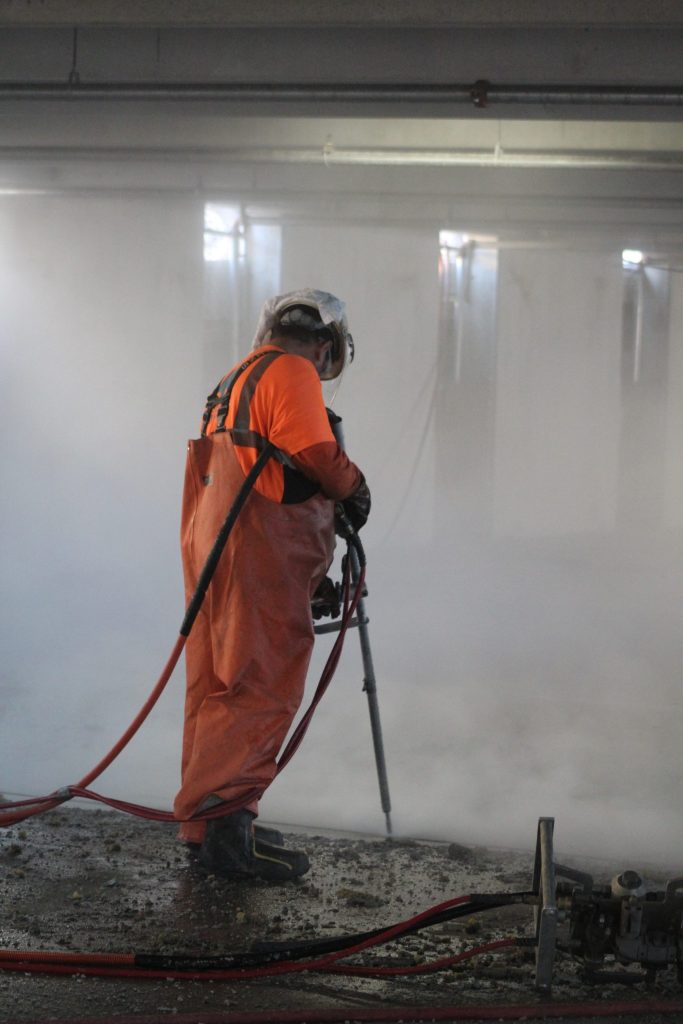 an operator using a hand lance to remove joint sealant in the parking garage.
