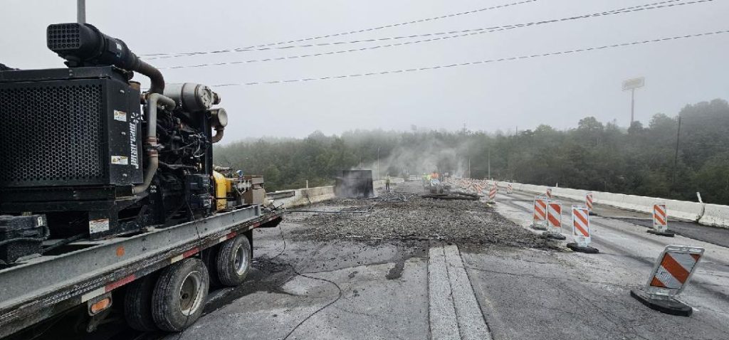 An operator using the vac truck attachments to clean up debris.